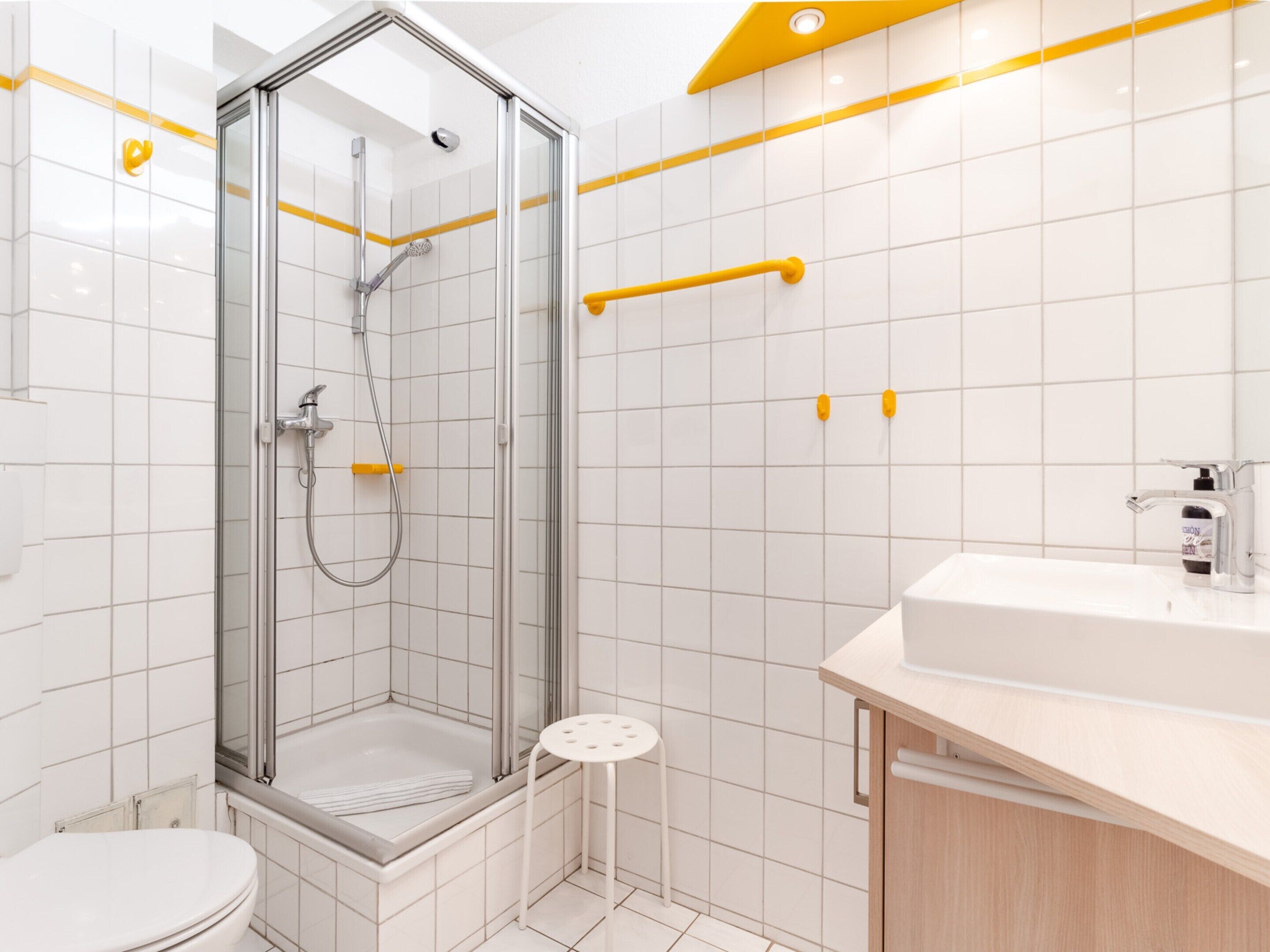Une salle de bain moderne avec une douche à parois de verre, des toilettes blanches et un lavabo avec un meuble en bois.