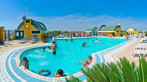 A swimming pool with people enjoying the water, surrounded by lounge chairs and umbrellas. - Residence Cristoforo Colombe Caorle (Caorle)