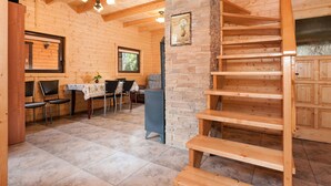 A wooden cabin interior with a dining area, a staircase, and a stone wall. - Chalet in Pobierowo Near Baltic Sea Beach (Rewal)