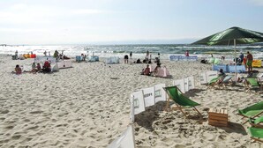 A beach with people sunbathing, umbrellas, and beach chairs. - Chalet in Pobierowo Near Baltic Sea Beach (Rewal)