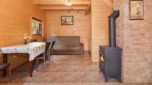 A wooden interior with a dining table, chairs, a sofa, a fireplace, and a ceiling light. - Chalet in Pobierowo Near Baltic Sea Beach (Rewal)