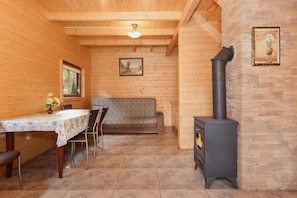 Un intérieur en bois comprenant une table à manger, des chaises, un canapé, une cheminée et un luminaire au plafond.