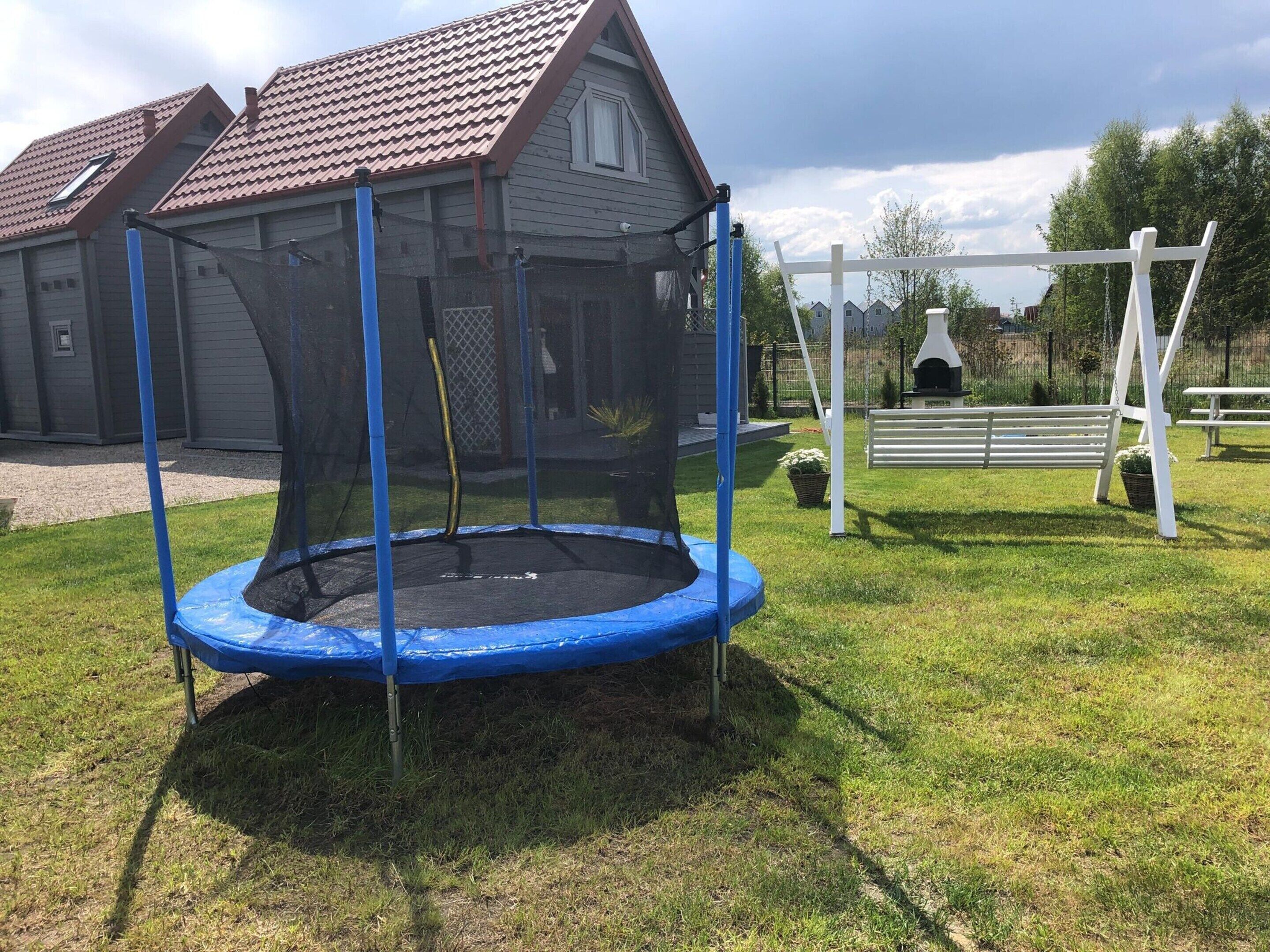 A trampoline with a safety net in a grassy yard.