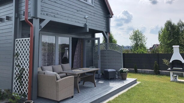 A grey house with a deck, outdoor furniture, and a barbecue grill. - Holiday Home in Niechorze With Garden (Rewal)