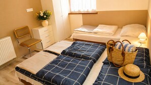 A bedroom with two beds, a chair, a wardrobe, a window with curtains, and a basket with a hat. - House by Lake Kolczewskie Near Baltic Sea (gmina Wolin)