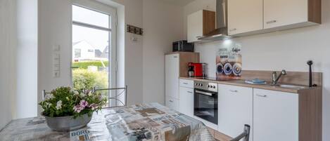 A modern kitchen with a built-in oven, a coffee machine, and a large window.