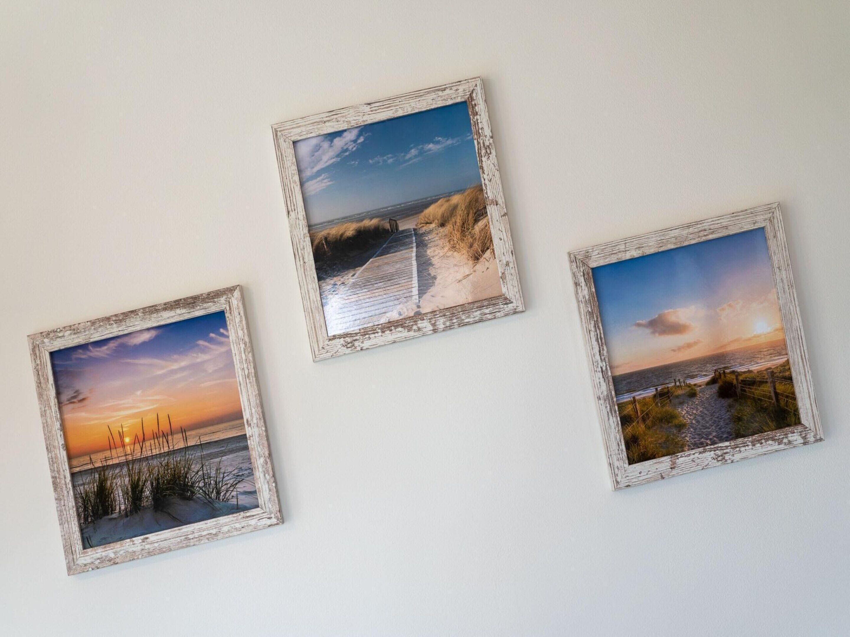 Three framed photographs of coastal scenes on a wall.