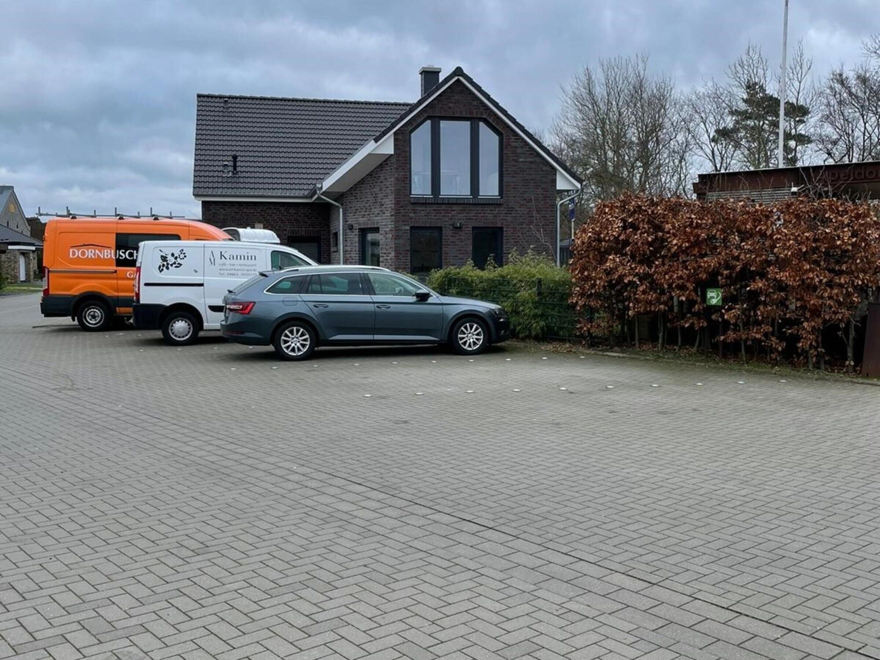 Een oprit van een woning met een geparkeerde auto en een bestelwagen.
