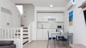 A modern kitchen with white cabinets, a microwave, and a dining area with a table and chairs. - TAO Caleta Playa, Corralejo (La Oliva)
