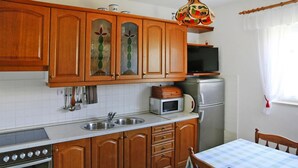 A kitchen with wooden cabinets, a microwave, a stove, and a refrigerator. - Apartment in Biograd Near Drazica Beach (Biograd na Moru)