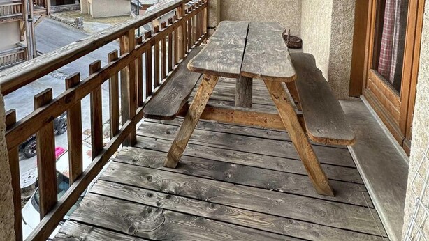 Une terrasse en bois avec une table et des bancs, offrant une vue sur un paysage montagneux.