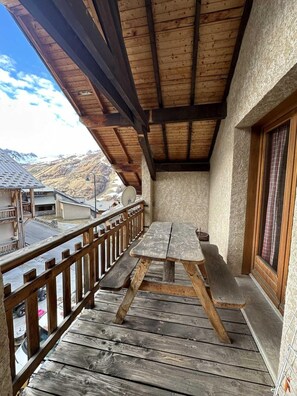 A wooden deck with a table and benches, overlooking a mountainous landscape.