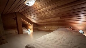Une chambre confortable située sous les toits, avec des murs en bois et un grand lit.