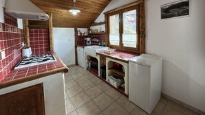 Une cuisine avec des poutres en bois, une cuisinière à gaz, un évier et une fenêtre.