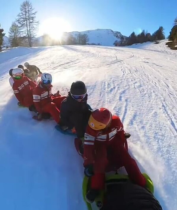 A group of people sledding down a snowy slope.
