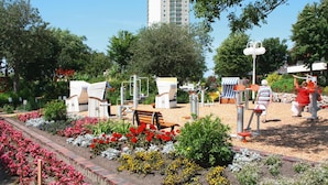 Un espacio al aire libre con equipo de ejercicio, un banco y una variedad de flores.