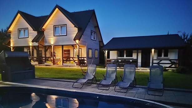 Ein zweistöckiges Haus mit Swimmingpool und Liegestühlen.