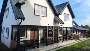 Ein modernes, zweistöckiges Haus mit einer Veranda und einem Kamin aus Backstein.
