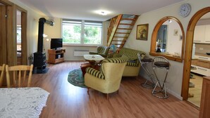 Un salon chaleureux avec une cheminée, un coin repas et une cuisine dotée de meubles en bois.