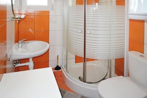 Un baño con ducha de vidrio, lavamanos e inodoro.