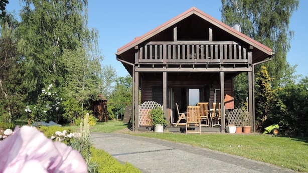 A wooden cabin with a porch, surrounded by a garden and trees. - Holiday Home Kolczewo Near Baltic Sea Beach (gmina Wolin)
