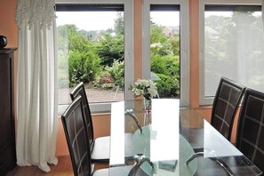 Enjoy meals in this dining area with a glass table and comfortable chairs, surrounded by a beautiful garden view.