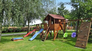 A wooden play structure with slides and a climbing wall in a grassy area. - Holiday Home Kolczewo Near Baltic Sea Beach (gmina Wolin)