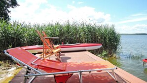 A wooden dock with a red lounge chair and a small table. - New Holiday Home in Nowe Warpno for 6 Persons (Nowe Warpno)