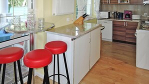 A kitchen with a central island, red bar stools, a white refrigerator, and wooden cabinets. - New Holiday Home in Nowe Warpno for 6 Persons (Nowe Warpno)