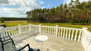 A covered outdoor area with a white balustrade, a round table, and two chairs. - Holiday Home in Nowe Warpno Near Harbor (Nowe Warpno)