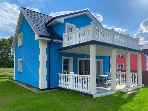 A two-story house with a blue exterior, a balcony with white balustrades, and a red section on the right. - Holiday Home in Nowe Warpno Near Harbor (Nowe Warpno)