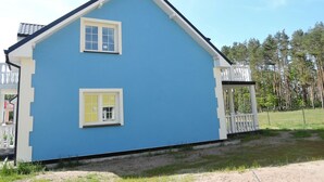 A two-story house with a blue exterior and white trim, featuring two windows and a small porch with a white railing. - Holiday Home in Nowe Warpno Near Harbor (Nowe Warpno)