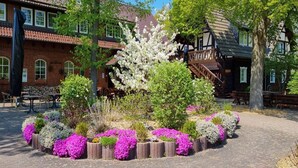 A courtyard with a brick building, wooden benches, and flowering plants.