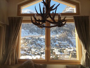 Une pièce dotée d’une grande fenêtre donnant sur une ville de montagne enneigée.