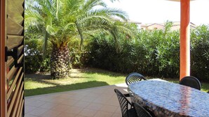 An outdoor patio with a table and chairs, surrounded by lush greenery and a palm tree. - Apartment in Monte Petrosu Near San Teodoro (San Teodoro)