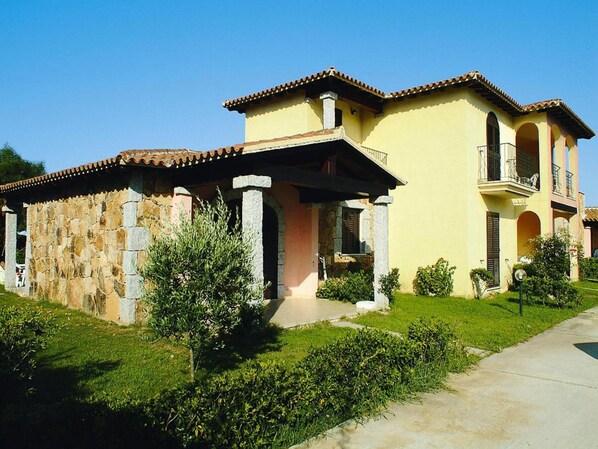 A two-story building with a stone facade and a yellow exterior. - Apartment in Monte Petrosu Near San Teodoro (San Teodoro)
