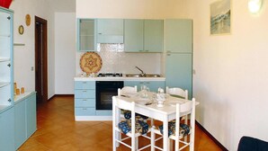 A compact kitchen with light blue cabinets, a white dining table, and chairs. - Apartment in Monte Petrosu Near San Teodoro (San Teodoro)