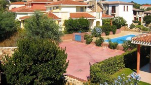 A residential area with houses, a swimming pool, and a stone wall. - Apartment in Monte Petrosu Near San Teodoro (San Teodoro)