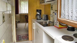 Une cuisine compacte équipée d’un four à micro-ondes, d’un grille-pain et d’une machine à café sur le plan de travail, ainsi que d’un évier avec un robinet.