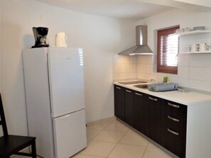 A compact kitchen with a refrigerator, a sink, and a window with blinds. - Tranquil Couples Retreat in Starigrad (Starigrad)