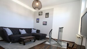 A modern living room with a sectional sofa, a coffee table, and a staircase. - Ferienwohnung am Aubach in Schwerin (Schwerin)