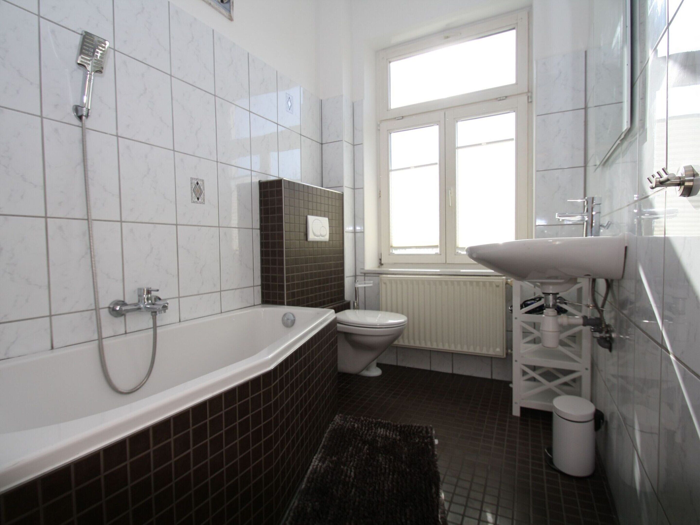 A bathroom with a bathtub, toilet, and window.