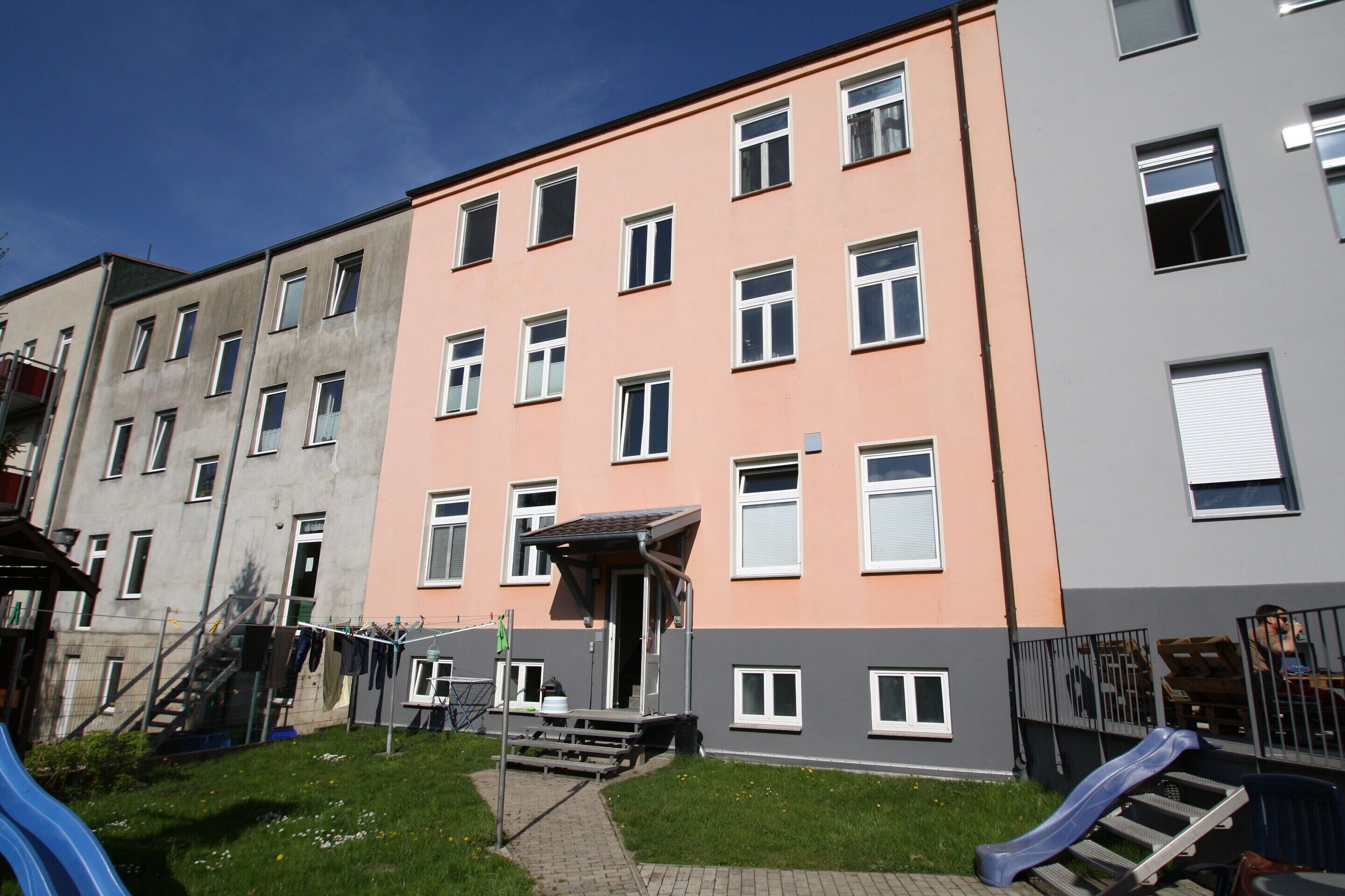 A multi-story residential building with a playground area including a slide and stairs.