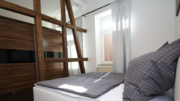 A bedroom with a bunk bed, a ladder, a window with curtains, and a bedside table. - Ferienwohnung am Aubach in Schwerin (Schwerin)
