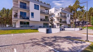 A modern multi-story residential building with balconies, large windows, and a paved driveway. - Nice, Cozy Apartment Very Close to the Beach (Rewal)