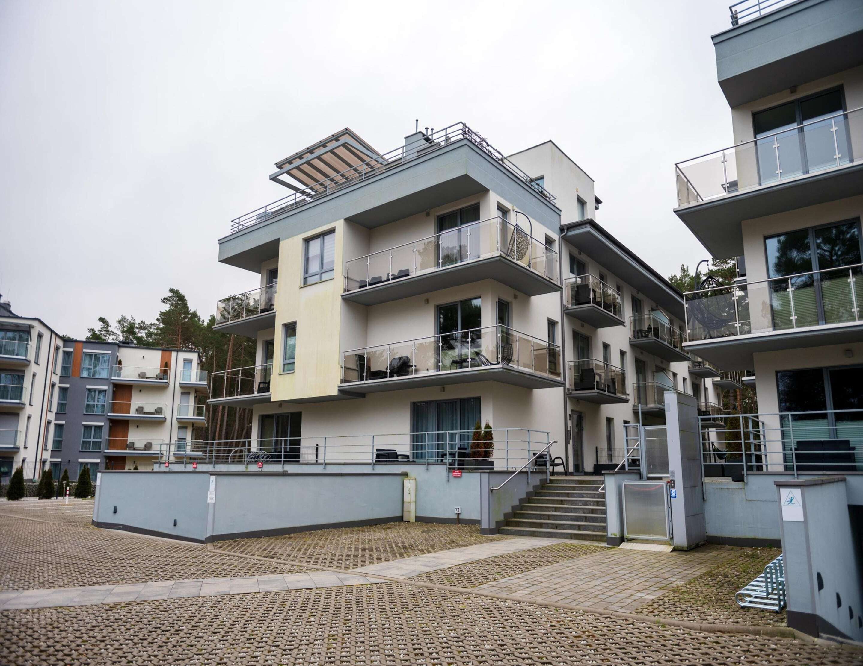 Een meerlaags woongebouw met balkons, een centrale trap en een geplaveid binnenterrein.