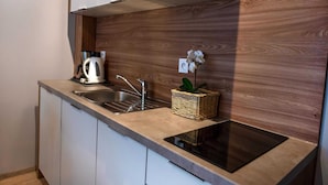 A modern kitchen with white cabinets, a stainless steel sink, a built-in stove, and a wooden backsplash. - Nice, Cozy Apartment Very Close to the Beach (Rewal)