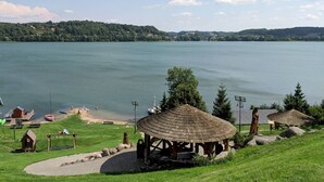 A lakeside park with a gazebo, picnic tables, and a small wooden cabin. - Holiday Home by the Lake, Sauna, Boat, Bicycles (Chmielno)