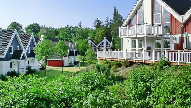 Uma fileira de casas modernas de dois andares com sacadas, rodeada por vegetação exuberante.