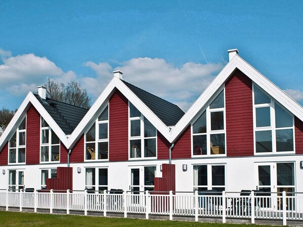 A row of red and white buildings with large windows and a white fence in front. - Reihenhauser im Schlosspark Bad Saarow (Bad Saarow)